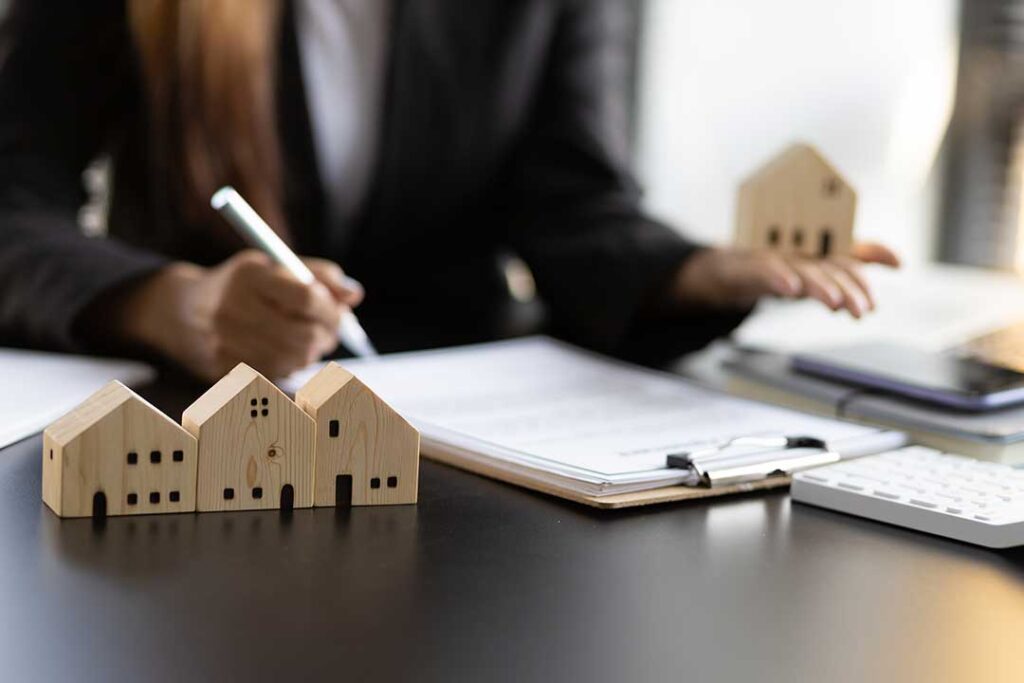 A friendly real estate agent showing home listings to a couple at a kitchen table.