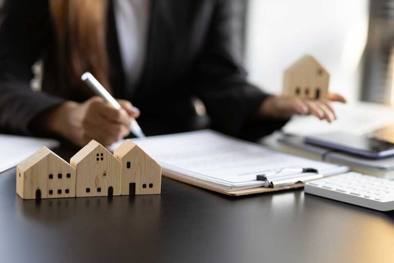 A friendly real estate agent showing home listings to a couple at a kitchen table.