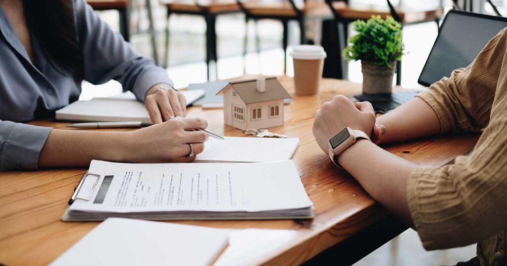 Two people arranging living room furniture and adding throw pillows to prepare a house for showing.